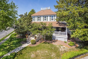 A two-story house with a porch, surrounded by trees and a well-maintained lawn.