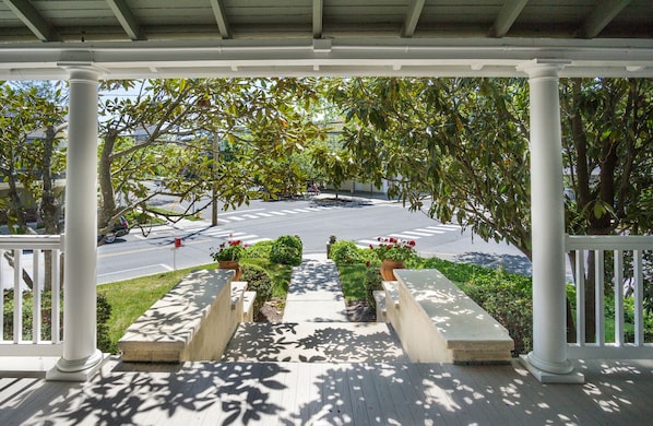 A covered porch with white columns, a crosswalk, and a street view.