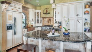 Una cocina amplia con muebles blancos, una isla de granito y salpicadero.