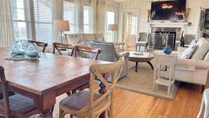 Un salon spacieux avec une table à manger en bois, des sièges confortables, un téléviseur et une cheminée.