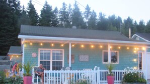 A house with a porch, a white picket fence, and string lights.