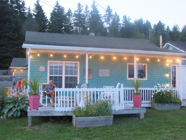 A house with a porch, a white picket fence, and string lights.