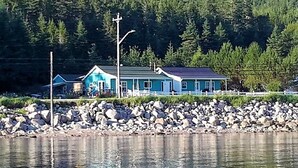 A house by a lake with a rocky shoreline.
