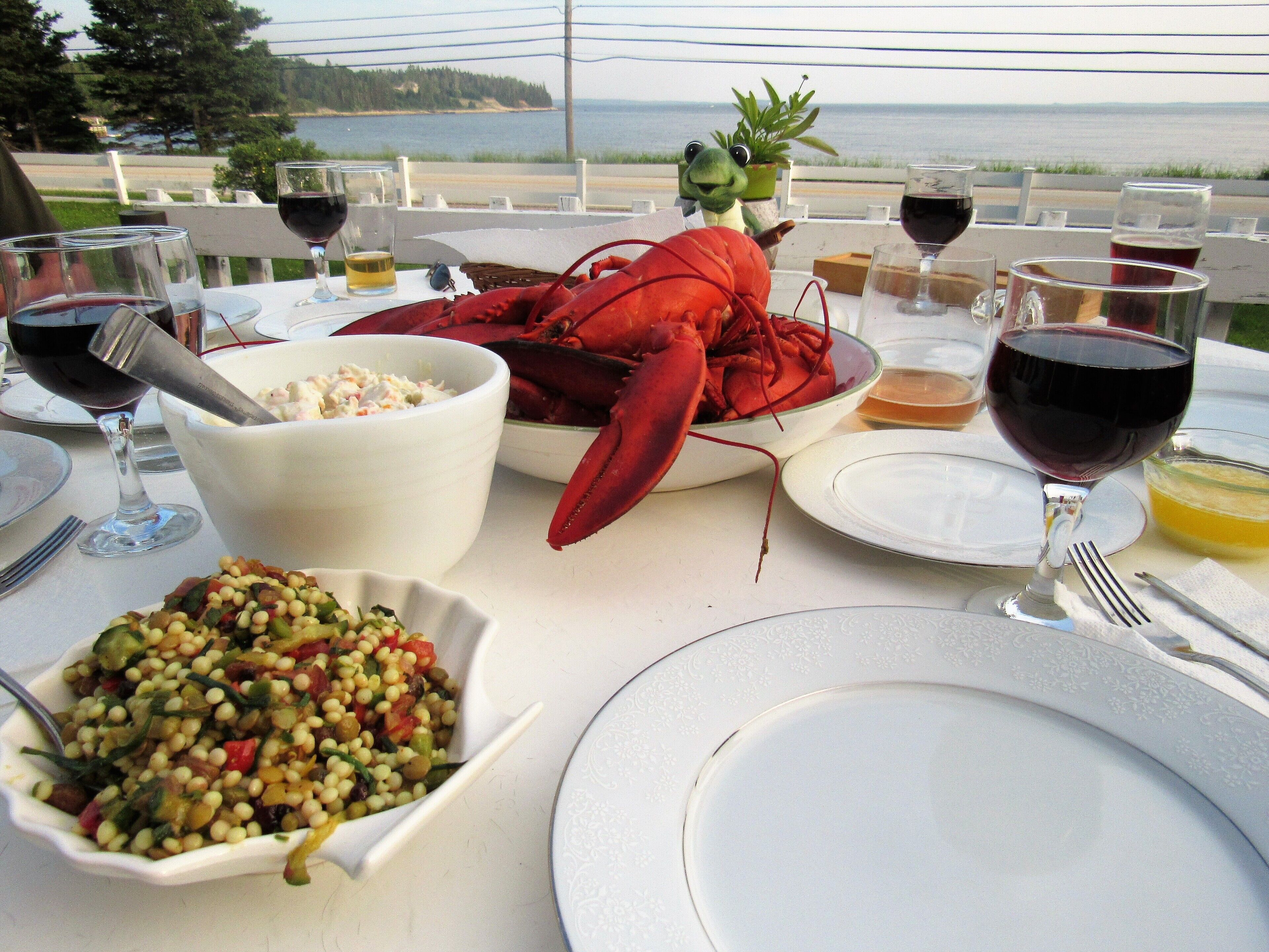 Mesa dispuesta para una comida con langosta, ensalada y copas de vino.