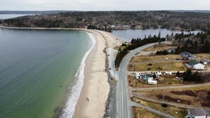 An aerial view of a coastal area with a beach, a road, and several buildings.