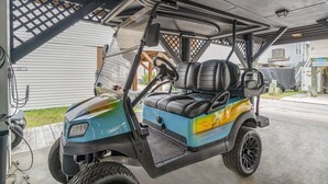 Un carrito de golf estacionado en un garaje cubierto con techo de celosía, volante y asiento.