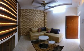 Cozy living space with a curved ceiling, ceiling fan, and patterned wallpaper.