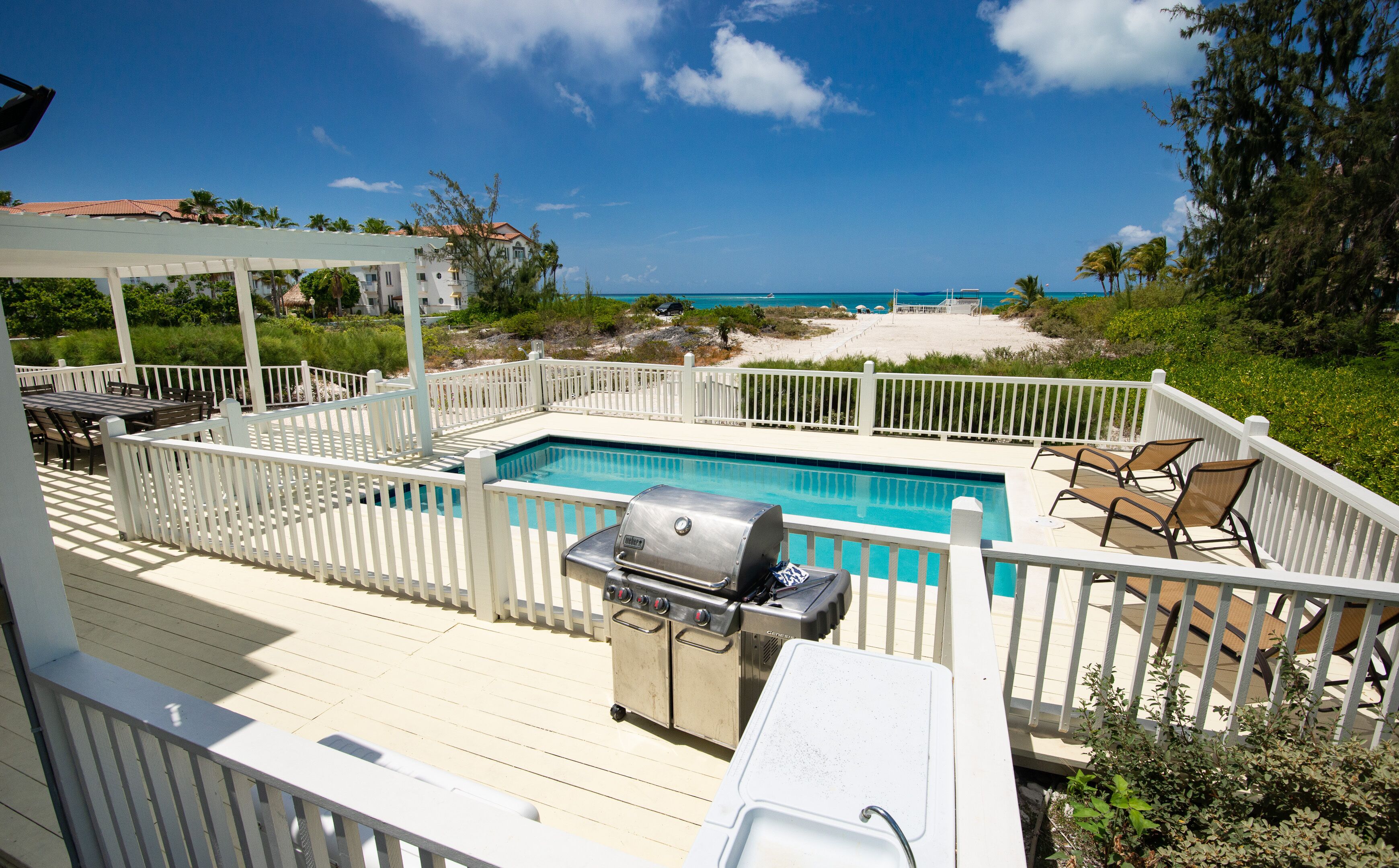 A deck with a pool, grilling area, and outdoor seating.
