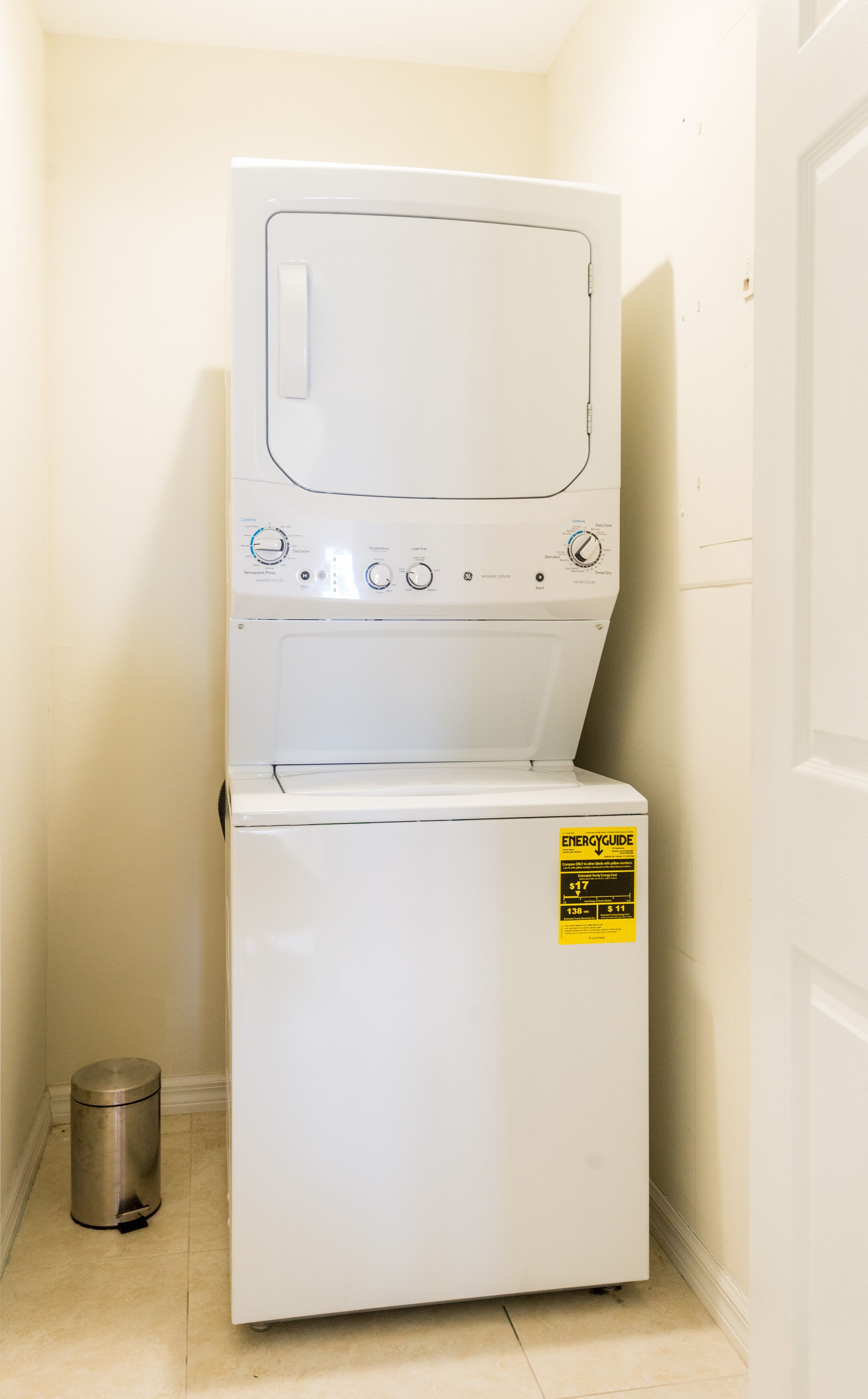 Un appareil compact, blanc, combinant lave-linge et sèche-linge, doté d’un panneau de commande offrant de nombreux réglages. Un autocollant jaune ENERGYGUIDE est apposé sur la façade.