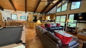 Un grand espace de vie comprenant une table de billard, un canapé en cuir et un téléviseur.