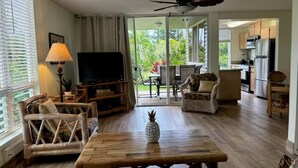 A spacious living room with a wooden coffee table, a television, and a ceiling fan.