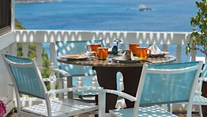 Un balcon avec une table dressée pour deux personnes, offrant une vue sur la côte.