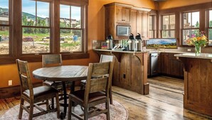 Una cucina rustica con mobili in legno, un tavolo da pranzo con sedie e vista sull'esterno.