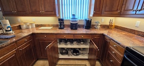 A kitchen with wooden cabinets, a granite countertop, a coffee maker, a toaster, and a knife block.