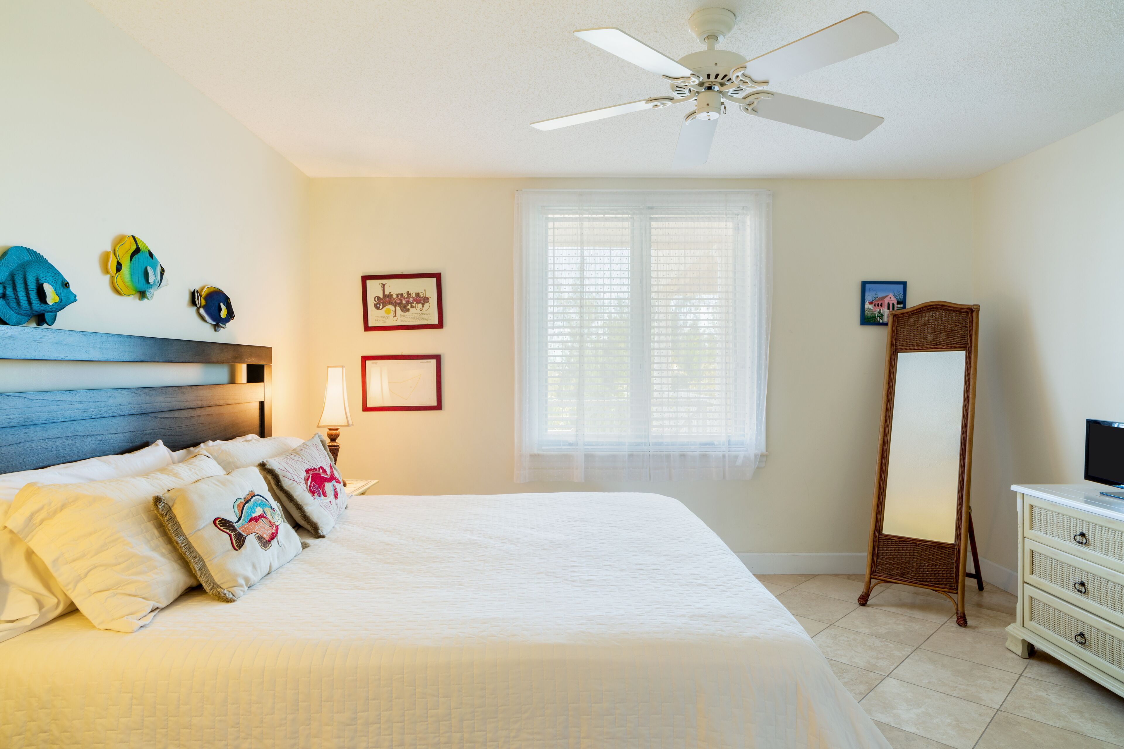 A bedroom with a bed, pillows, a dresser, a mirror, and wall decorations.