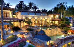 A resort with a pool, outdoor seating, and a well-lit building with arches.