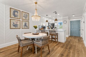 Un coin repas avec une table ronde, des chaises en osier et un lustre.