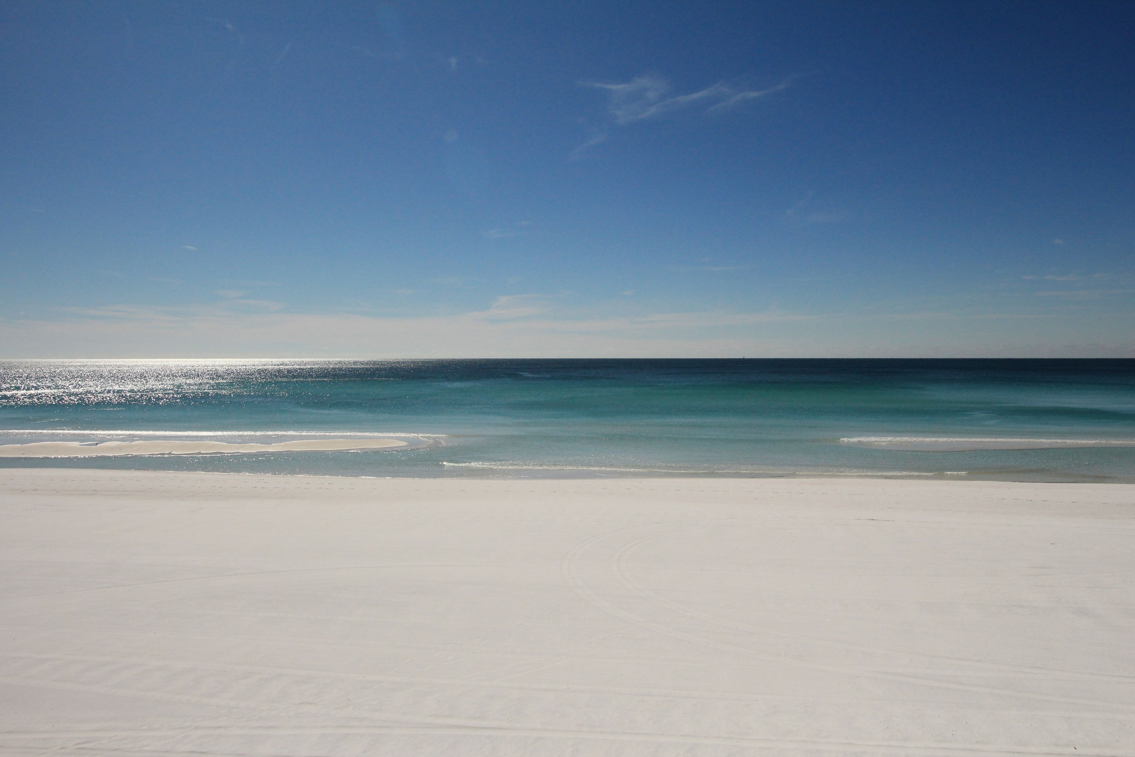 Une plage avec un ciel dégagé et une mer calme.