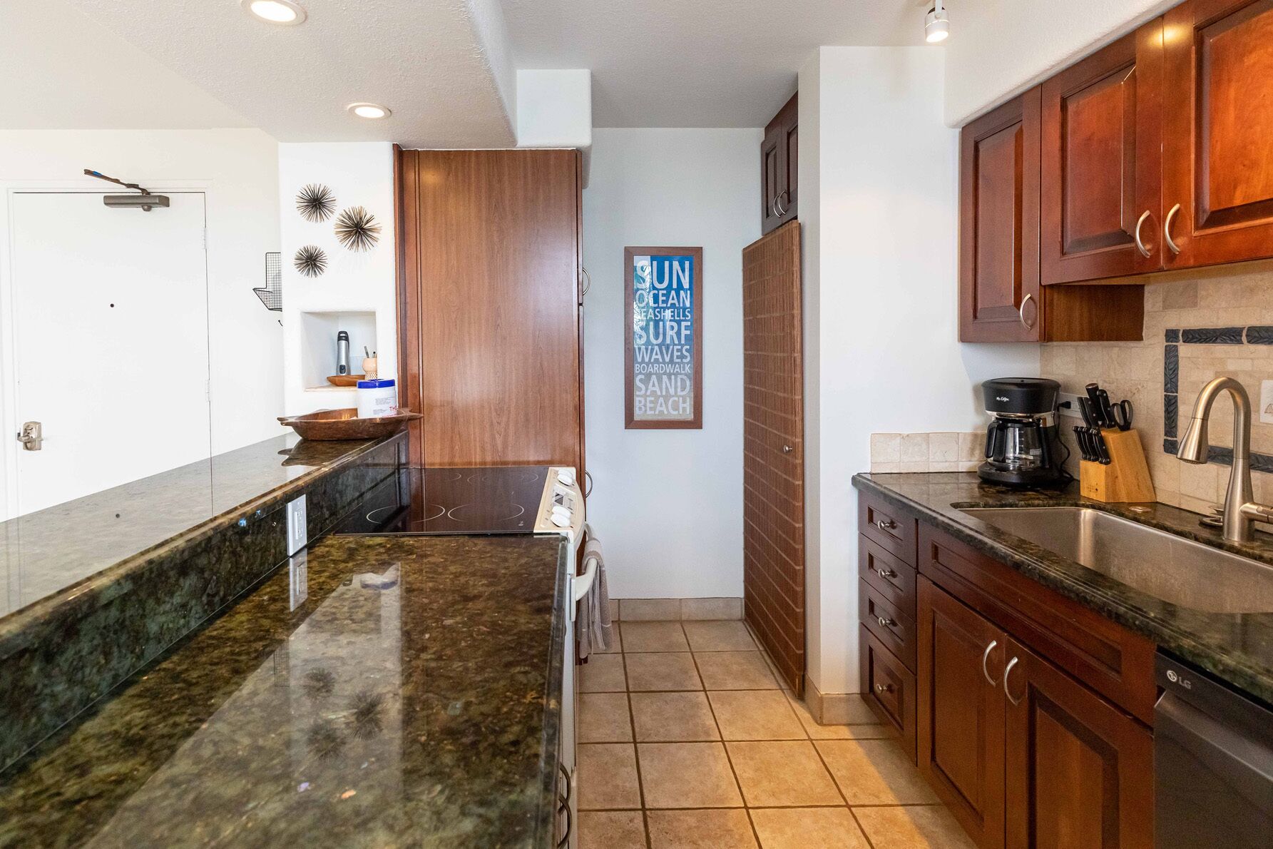 A kitchen with dark granite countertops, wooden cabinets, and a coffee maker.