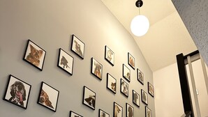 A staircase with a handrail and carpeted steps leading to a landing where multiple framed photographs are displayed on the wall.