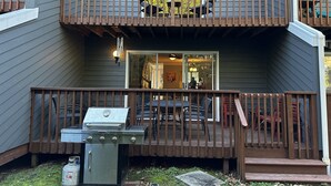 A two-story house with a balcony, a grill, and a dining area.