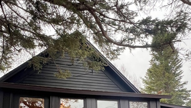 Une cabane en bois avec un porche, des fenêtres décorées de guirlandes et une lanterne sur la balustrade.