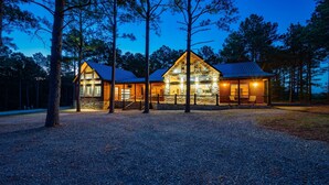 Une cabane avec une façade en pierre, de grandes fenêtres et une terrasse en bois.
