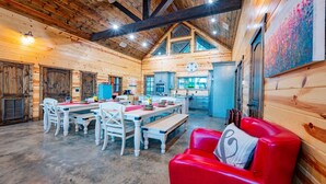 L’intérieur d’une cabane en rondins comprend un coin repas, une cuisine et un canapé en cuir rouge.