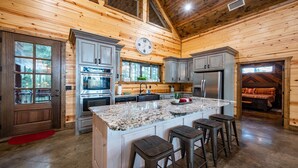 Une cuisine de style rustique, avec des comptoirs en granit, des appareils en acier inoxydable et un îlot central doté de tabourets de bar.
