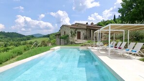 Relax by the serene pool surrounded by lush greenery and rolling hills.