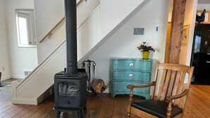 Une pièce avec un poêle à bois noir, un fauteuil à bascule en bois et une commode de couleur turquoise.