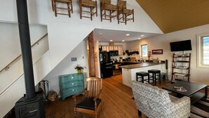 Un vaste espace de vie doté d’un haut plafond, de planchers en bois, d’une cuisine intégrée et d’un coin salon confortable.