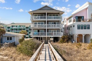 A multi-story hotel with balconies, a wooden walkway leading to the entrance, and a beach view. - Mimi's Place - Oceanfront condo, fantastic views and covered deck (Carolina Beach)