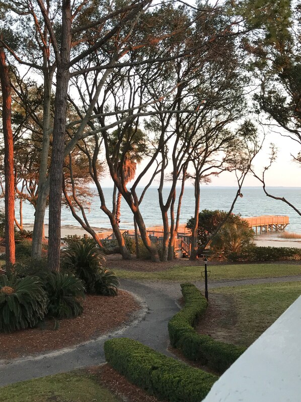 A pathway leading to a beach with trees and a wooden structure.