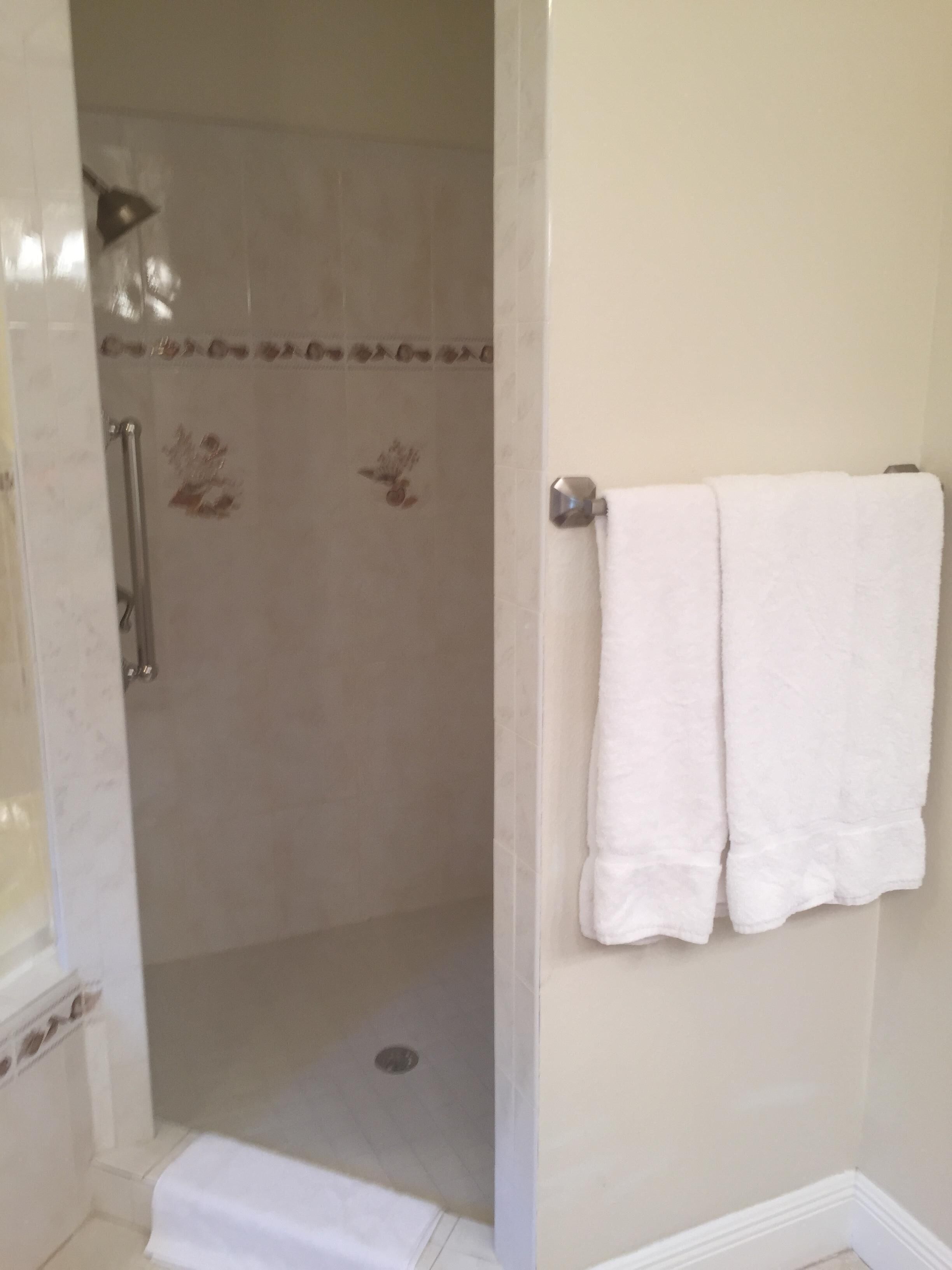 Een badkamer met een douche, toilet en een handdoekrek.