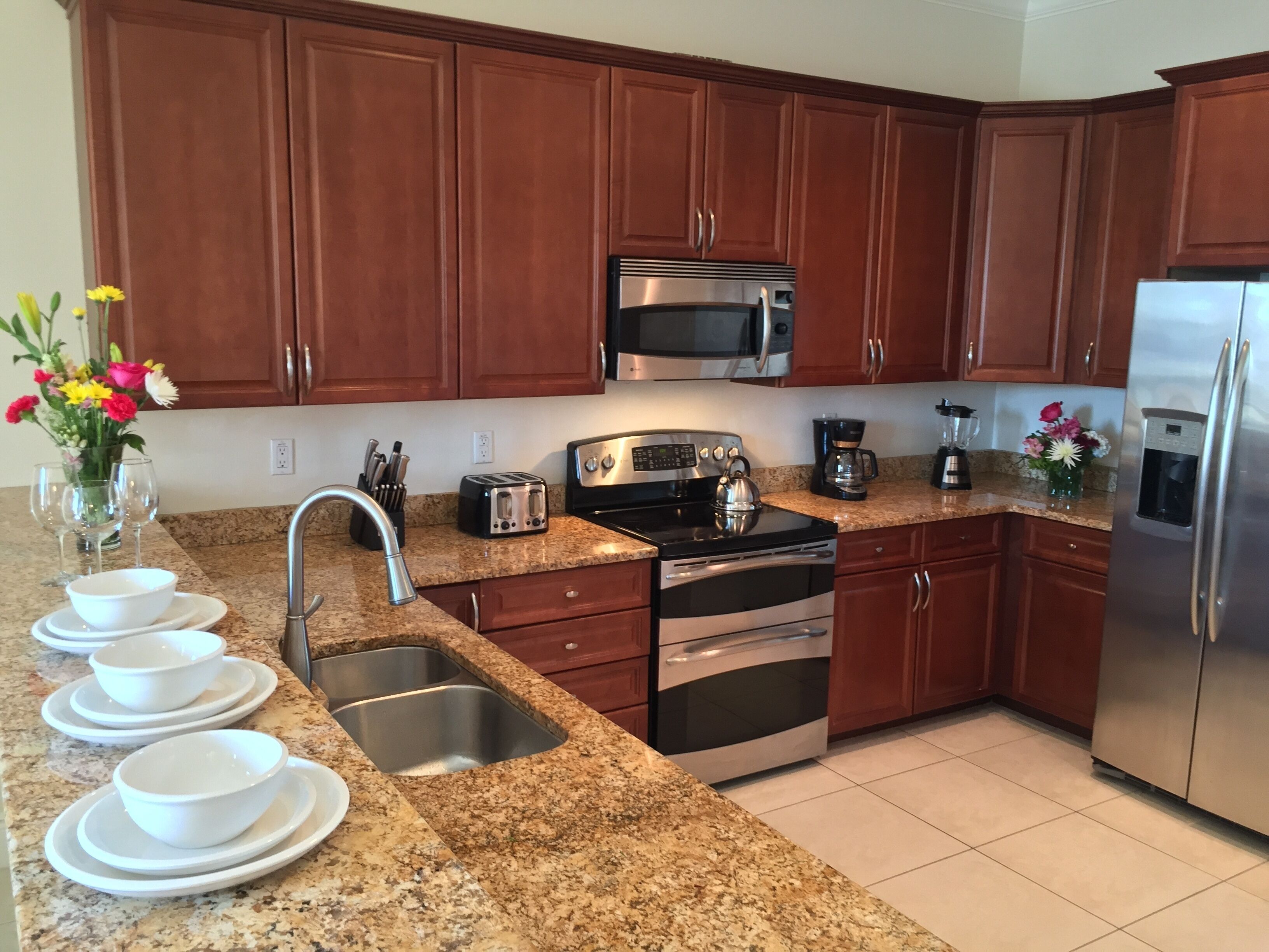 A modern kitchen with granite countertops, stainless steel appliances, and wooden cabinets.