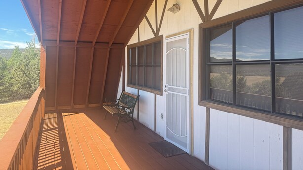 A covered porch with wooden beams, a bench, and a door with a window. - Mountain vacation getaway/Hunters paradise (Young)
