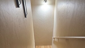 A wooden staircase with a handrail, leading to a landing with a light fixture. - Mountain vacation getaway/Hunters paradise (Young)