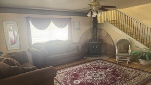 A living room with a sofa, a patterned rug, a fireplace, and a staircase. - Mountain vacation getaway/Hunters paradise (Young)