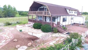 A two-story house with a porch, a stone pathway, and a fenced yard. - Mountain vacation getaway/Hunters paradise (Young)