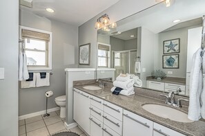 Een moderne badkamer met twee wasbakken, een grote spiegel en een handdoekhouder.