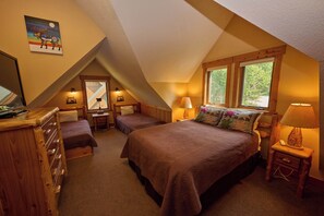 Een gezellig slaapkamer op zolder met twee bedden, een kaptafel en een raam met uitzicht op bomen.