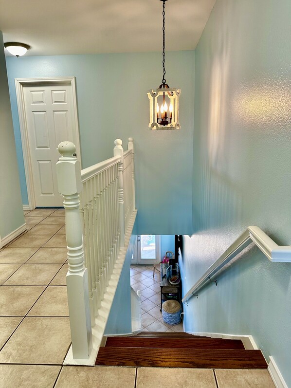 A staircase with white balusters and a wooden handrail, leading to a landing with a light fixture.