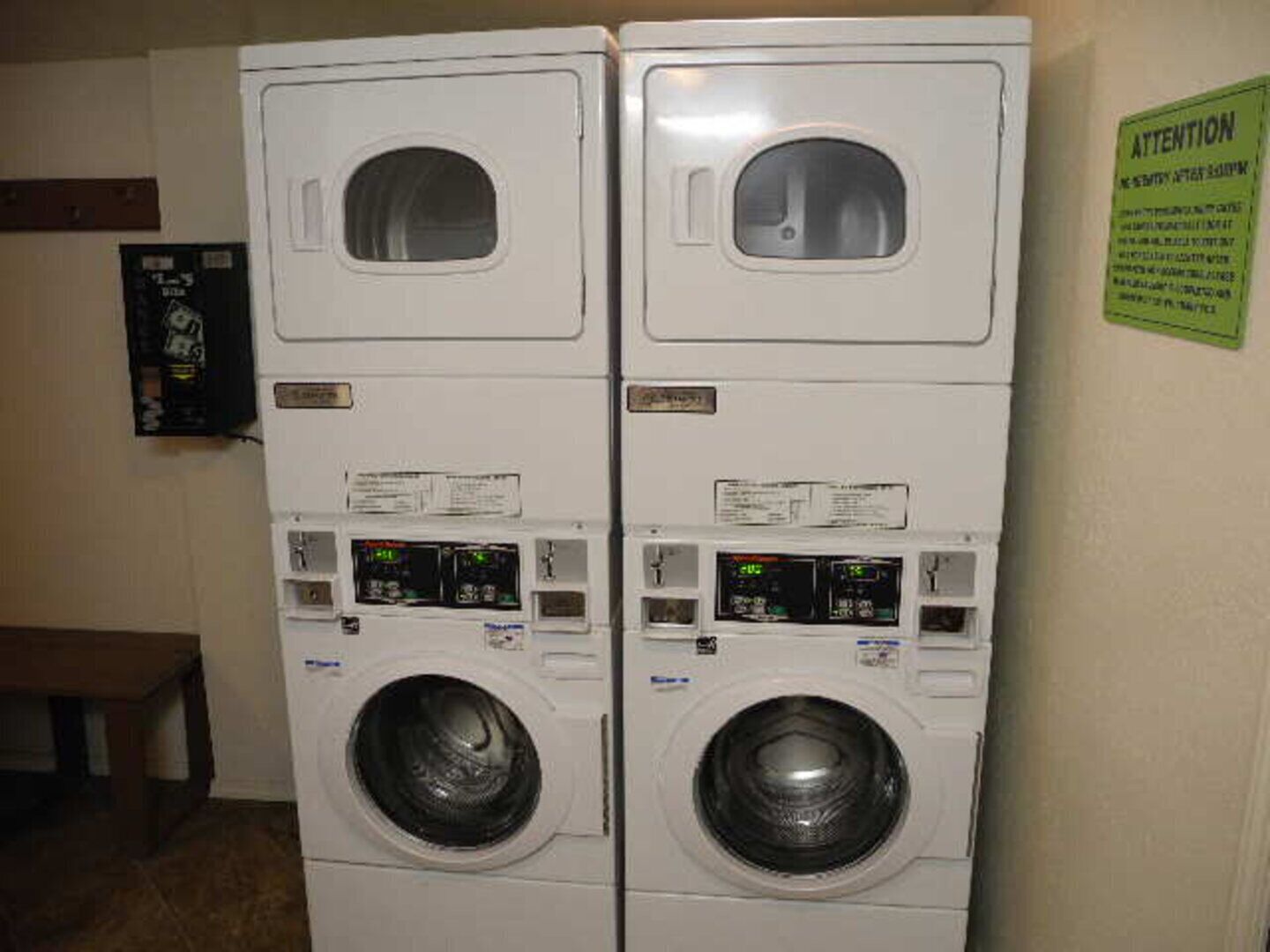 A laundry room with two stacked front-loading washing machines and a control panel.