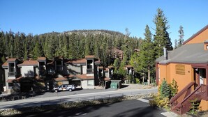 A multi-story building with a parking lot in front. - Courchevel 56 (Mammoth Lakes)