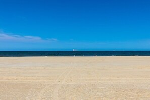 A wide sandy beach with a clear blue sky and calm sea.