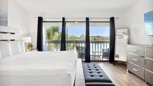 A modern hotel room with a large bed, a desk, and a view of the outdoors. - 2 STORY WITH 2 PRIVATE BALCONIES! 150 STEPS FROM BEACH! (Miramar Beach)