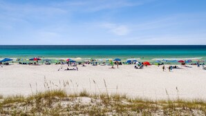 A beach with white sand, clear blue water, and colorful umbrellas. - 2 STORY WITH 2 PRIVATE BALCONIES! 150 STEPS FROM BEACH! (Miramar Beach)