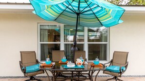 A patio table with chairs, a striped umbrella, and a pitcher on the table. - Arlington Park  Amazing Location   Pet Friendly  2 Master Suites Home (Sarasota)