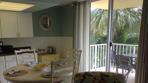A dining area with a round table, chairs, and a view of a balcony with outdoor furniture. - Gorgeous Condo and Ideal Vacation! Steps to Beach! Great couples get-away (Marco Island)